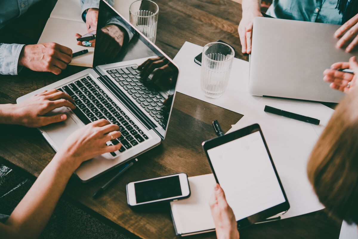 Overhead view of business team sitting around a table using a variety of mobile devices