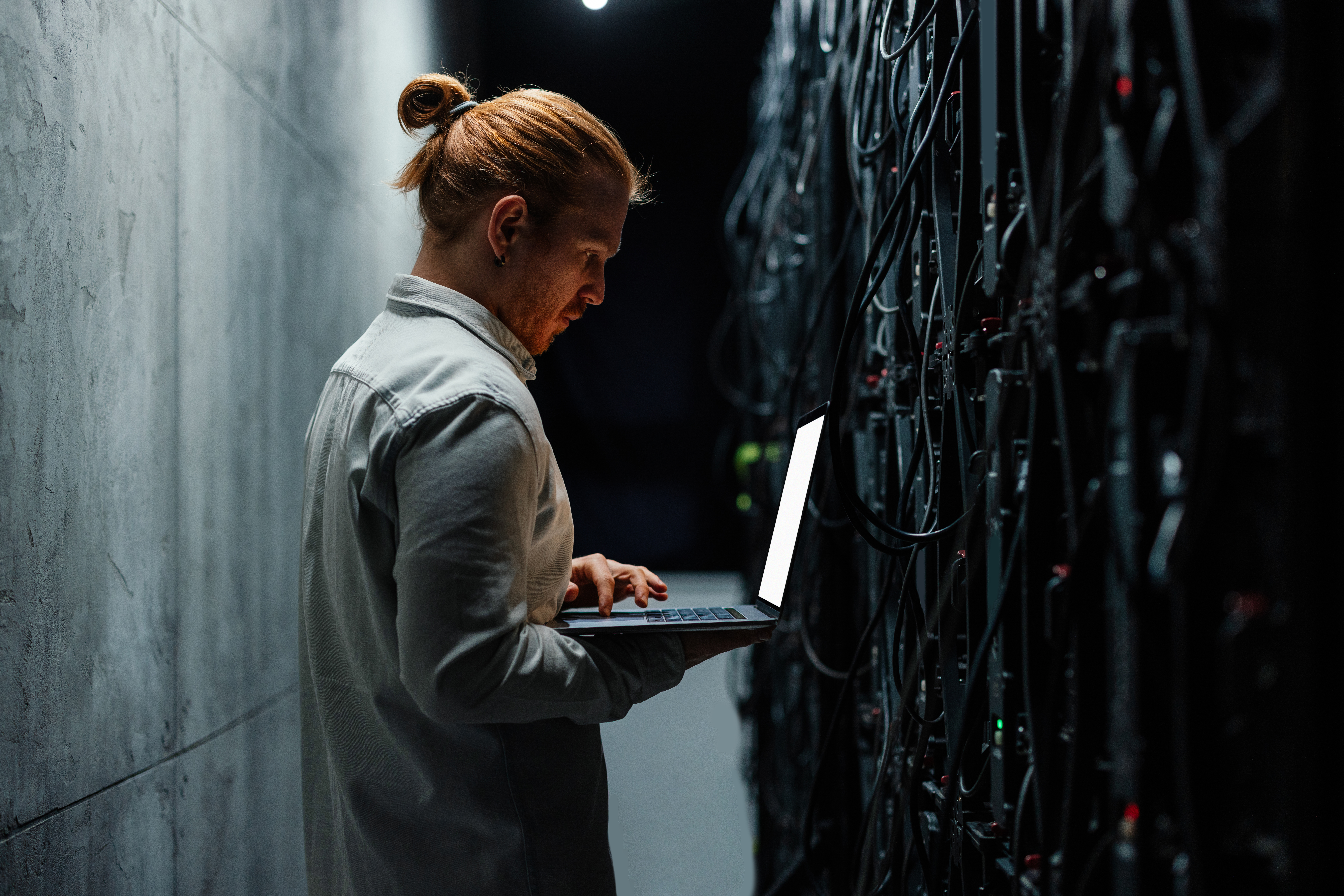 IT specialist working on a laptop in a server room