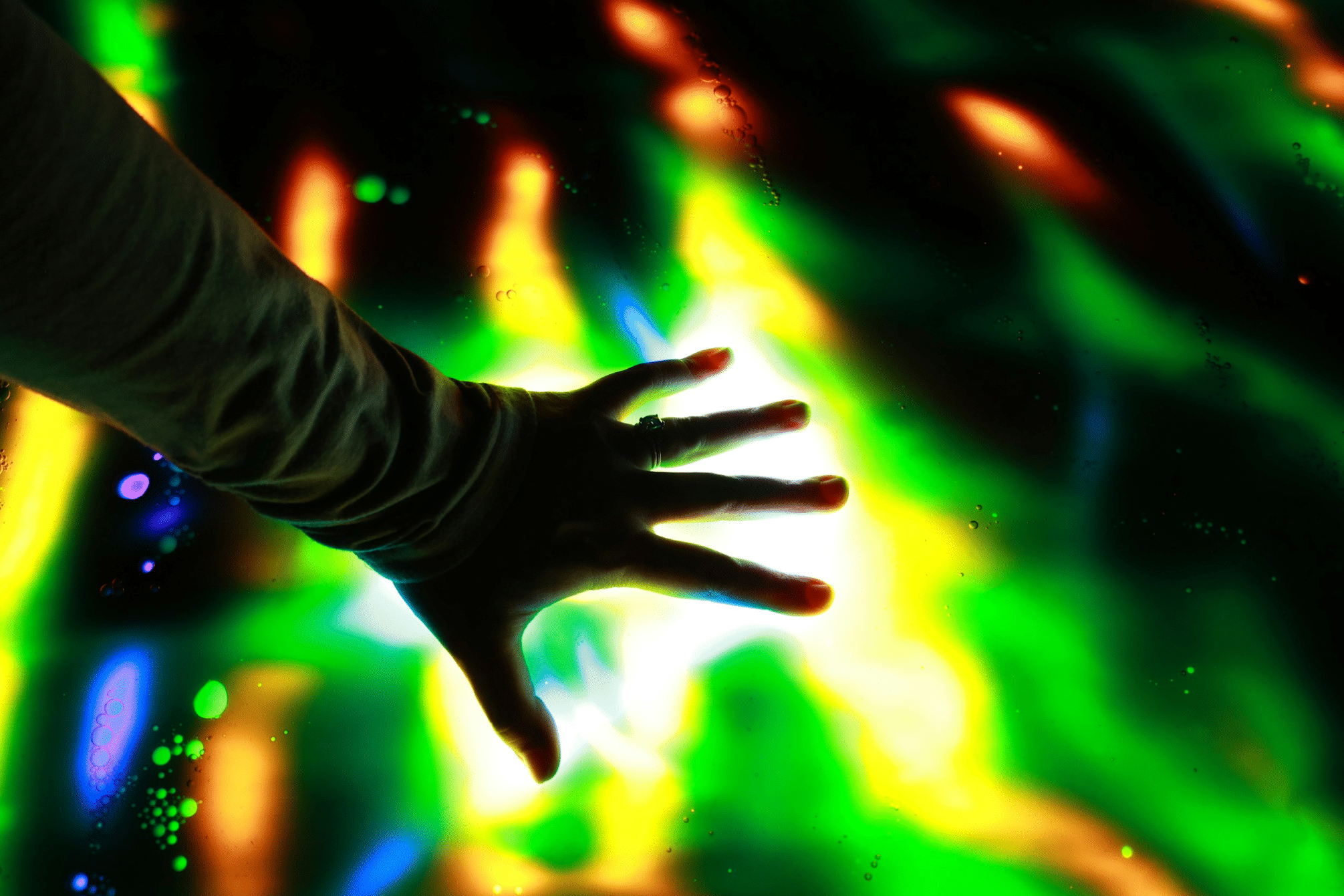 Close up of woman's hand touching illuminated and multi-coloured LED display screen, connecting to the future. People, lifestyle and technology