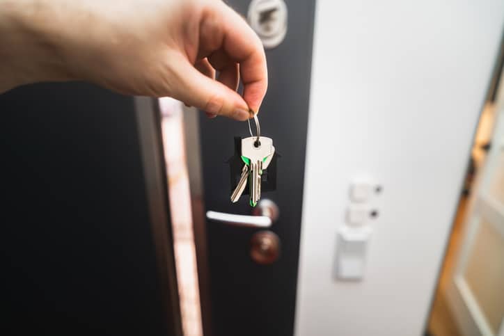 Closeup of a person's hand holding keys in front of a door.